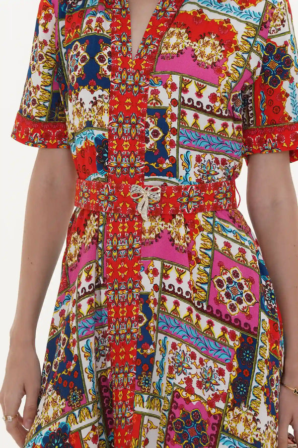 Close-up of Pretty Pixie red and pink patchwork-print belted V-neck dress with crystal bow brooch