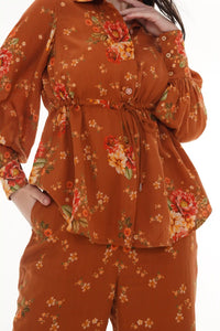 Woman in Pretty Pixie rust floral belted shirt & flare pants co-ord set, close-up of drawstring waist and puff sleeves