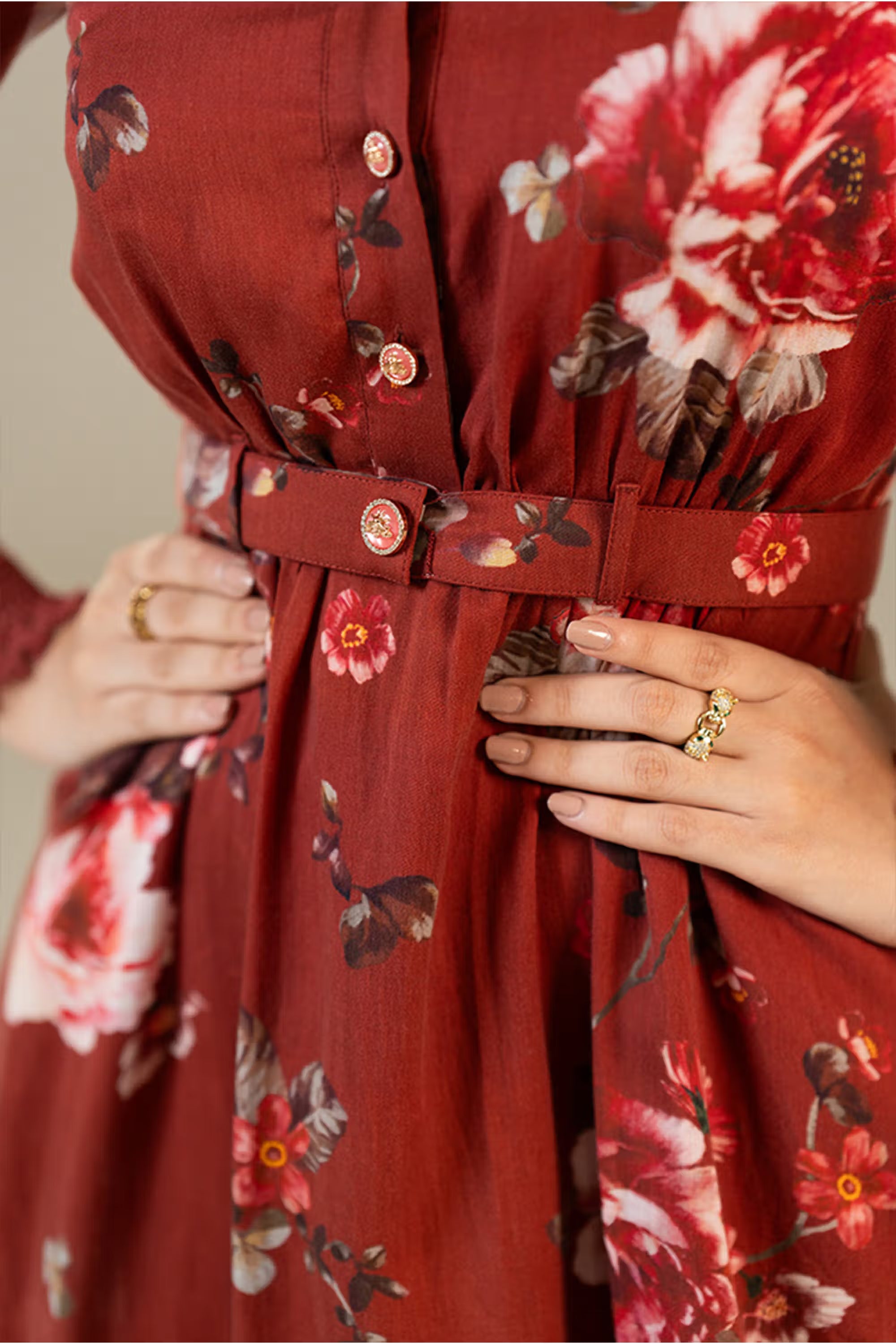 Closeup of waist belt and button-front detail on rust red floral shirt dress with floral prints