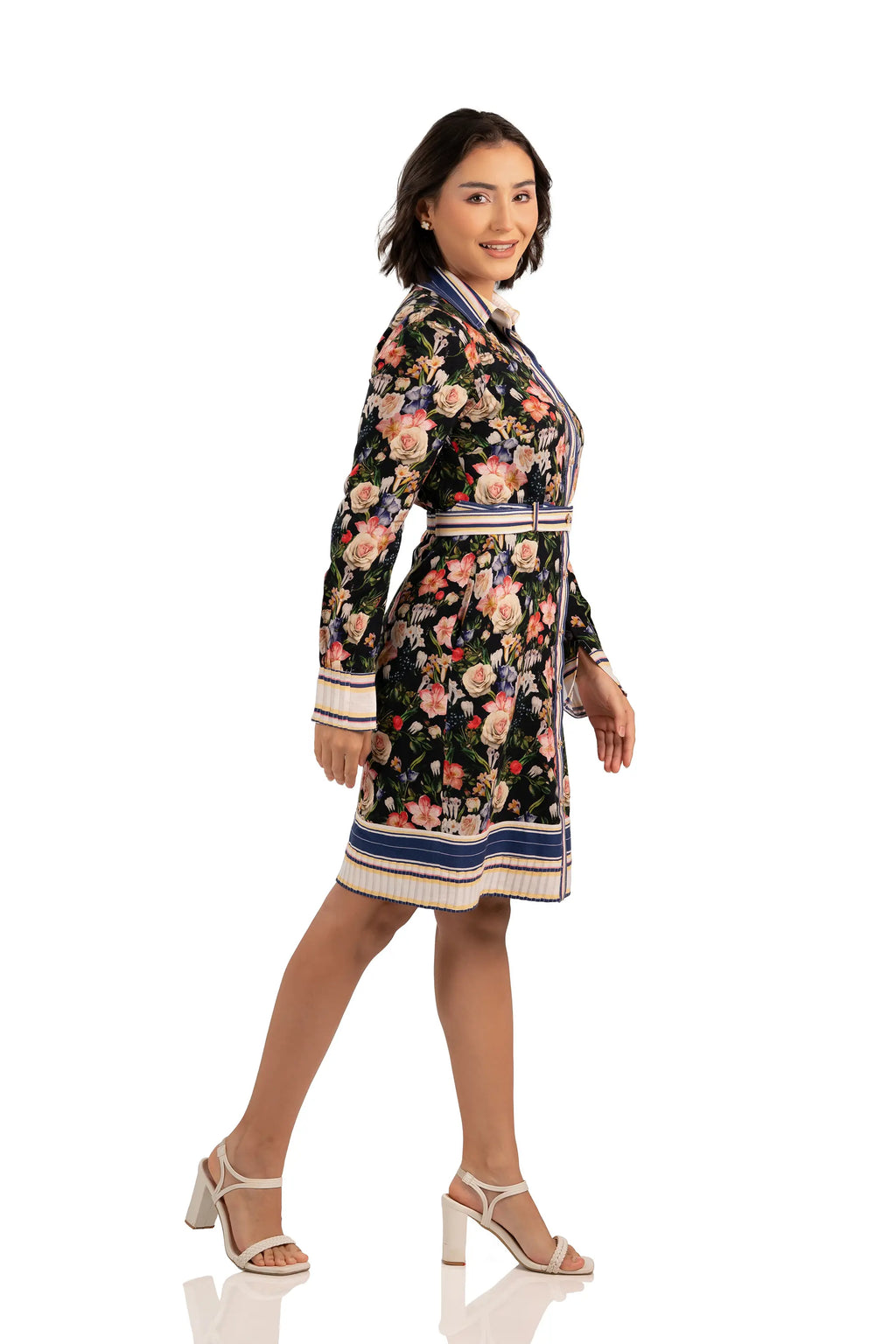 Model in side profile wearing black floral shirt dress with belted waist, long sleeves, and striped cuff details.