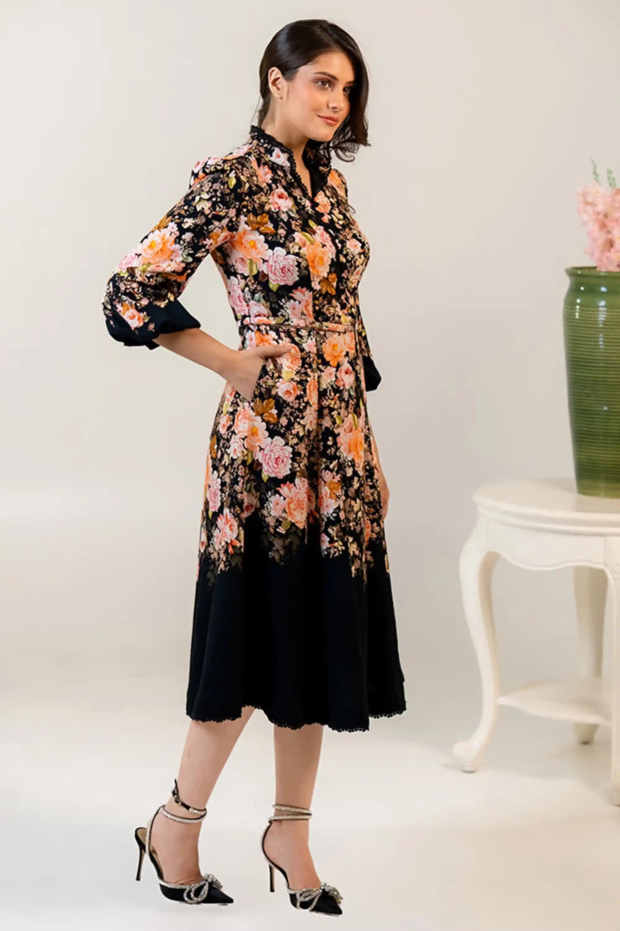 Woman smiling in black floral midi dress with rose patterns
