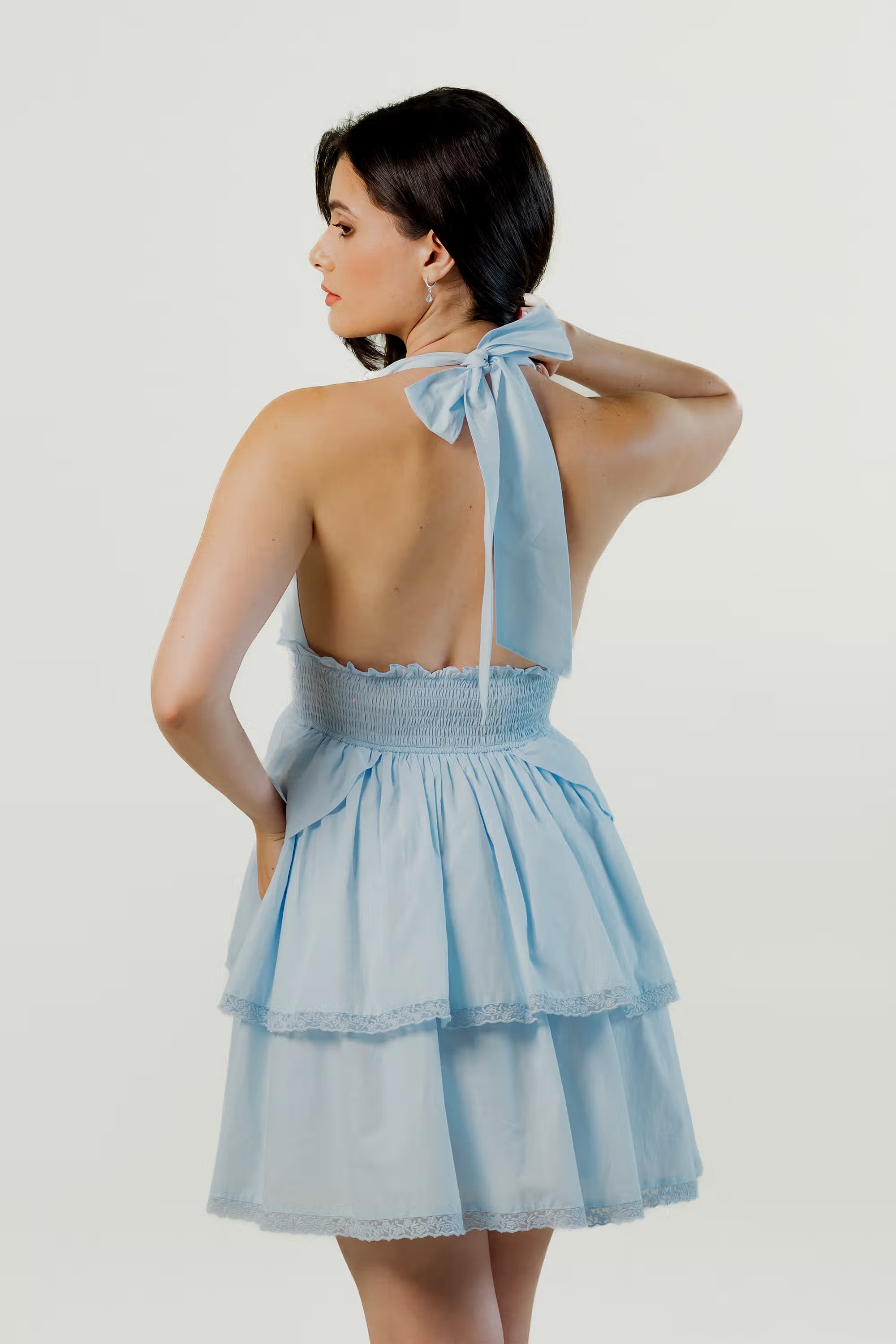 Back view of sky blue halter mini dress with bow tie and layered skirt