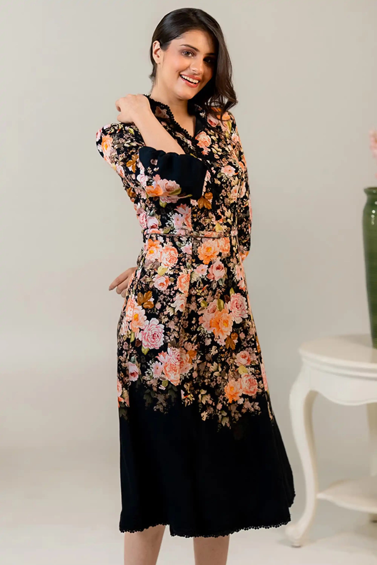 Woman smiling in black floral midi dress with rose patterns