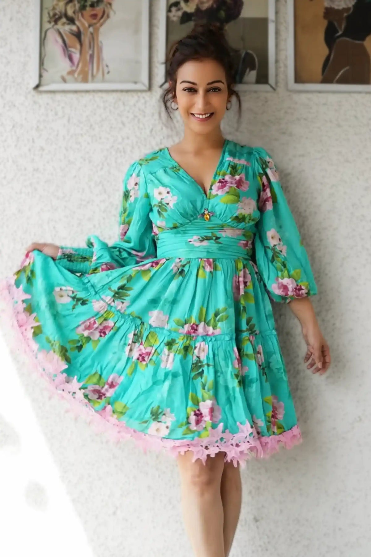 Sunayana Fozdar wearing a turquoise floral dress with a flowing silhouette, posing indoors against a textured wall during a fashion pretty pixie.