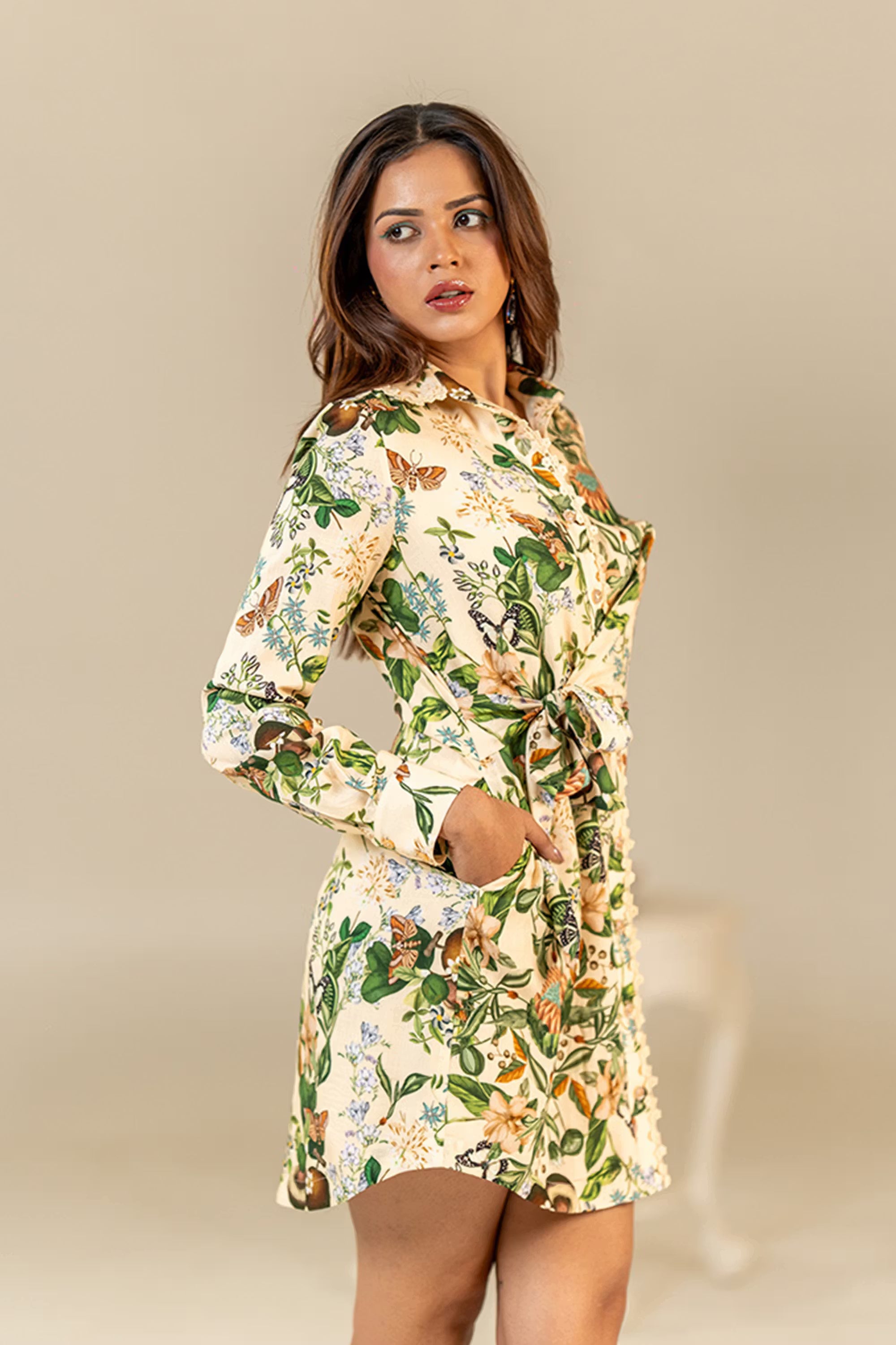 Women in a cream floral butterfly shirt dress, showing side profile with waist tie belt detail.