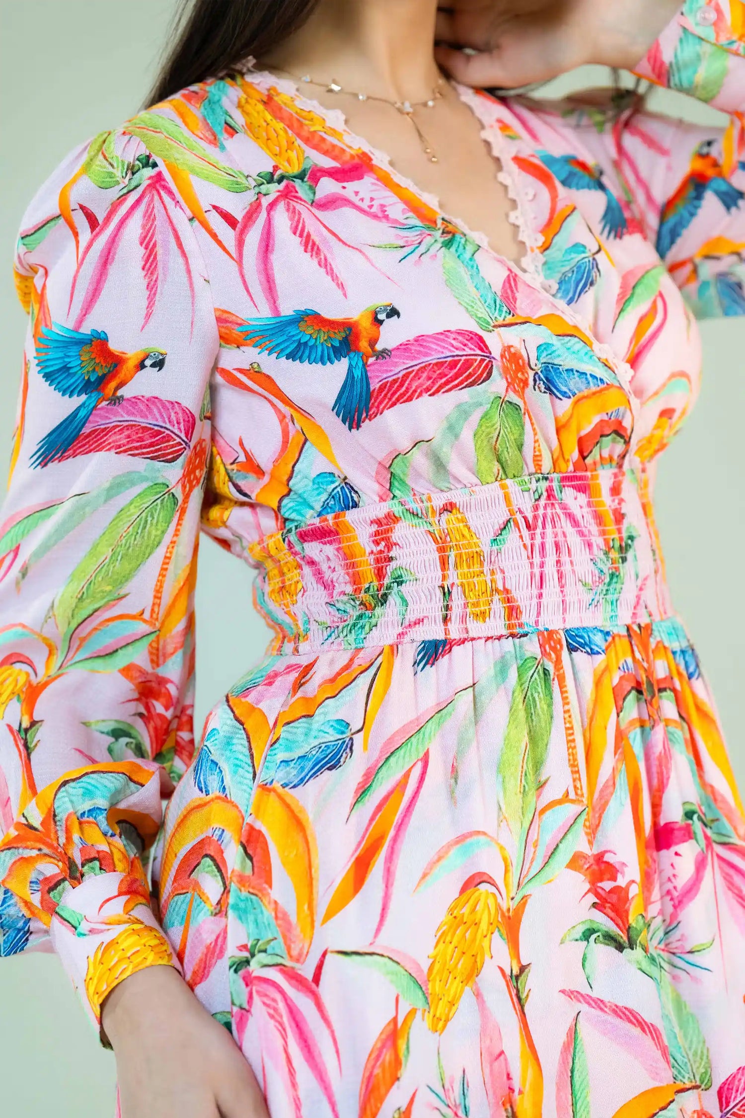 Side detail of tropical parrot print pink dress with smocked waist