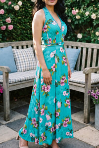 Side view of turquoise floral halter maxi dress with pink botanical print on woman; organic cotton vacation and occasion wear