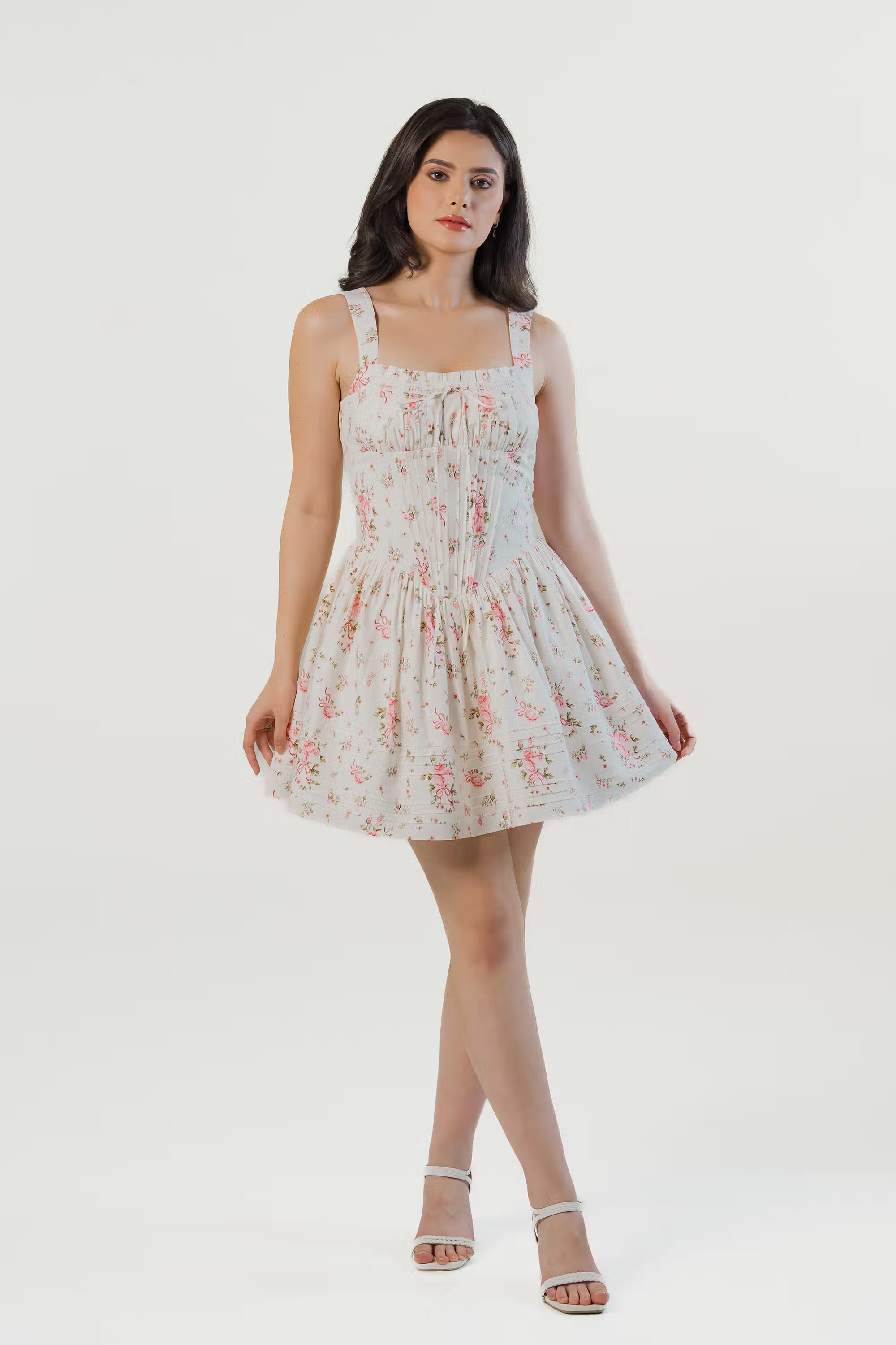 Front view of white floral corset mini dress with puff sleeves and flared hem, styled with strappy heels
