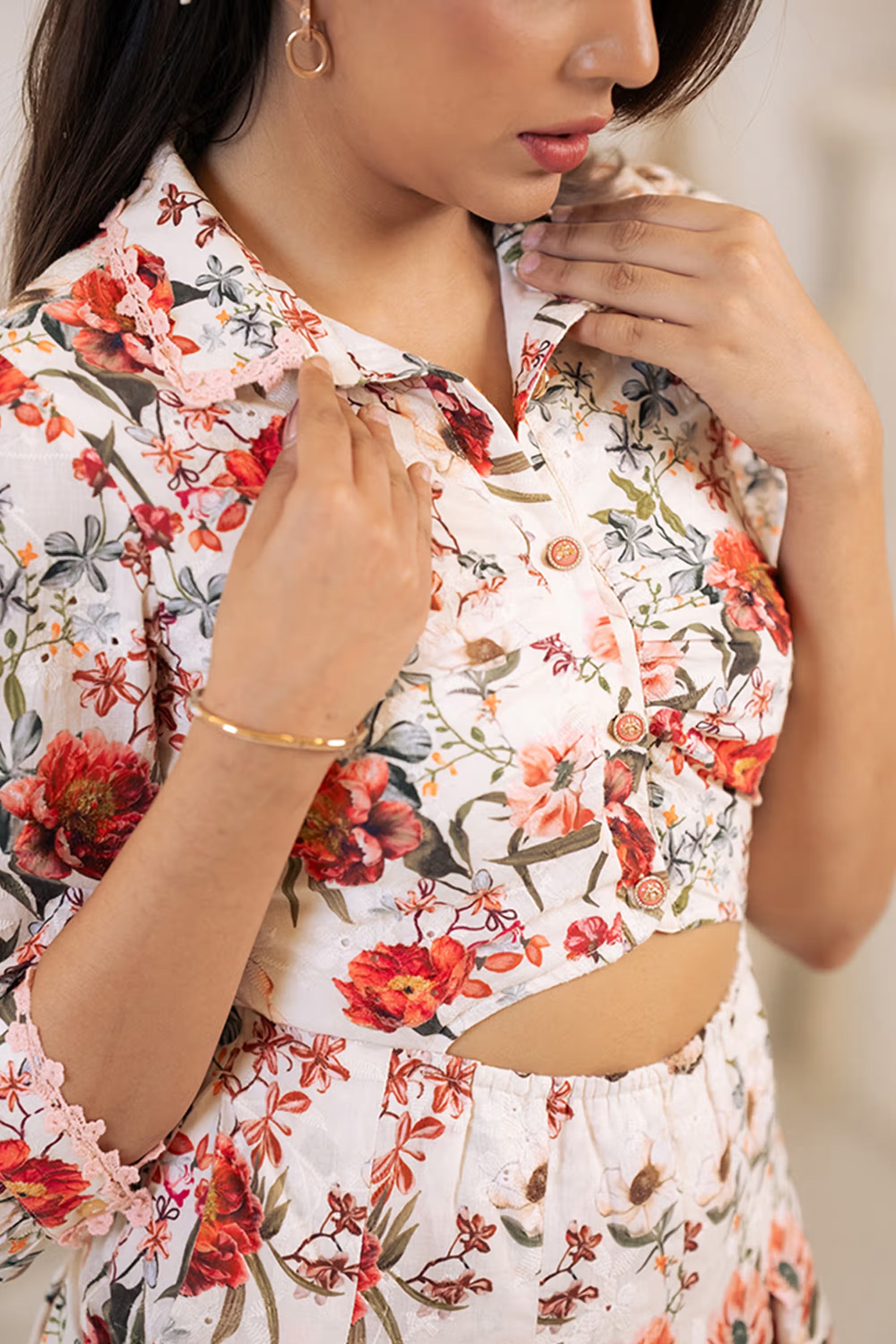 Detailed closeup of buttons and embroidered red floral prints on white cutout shirt dress