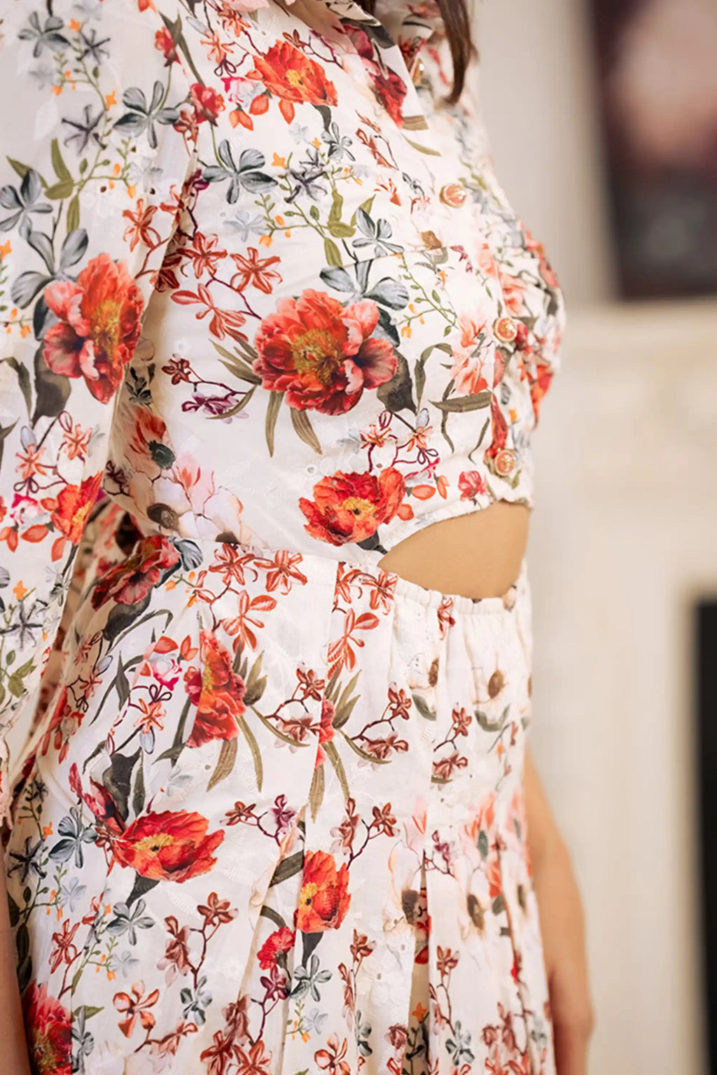 Fabric closeup of white floral cutout dress with red and orange flower print details.