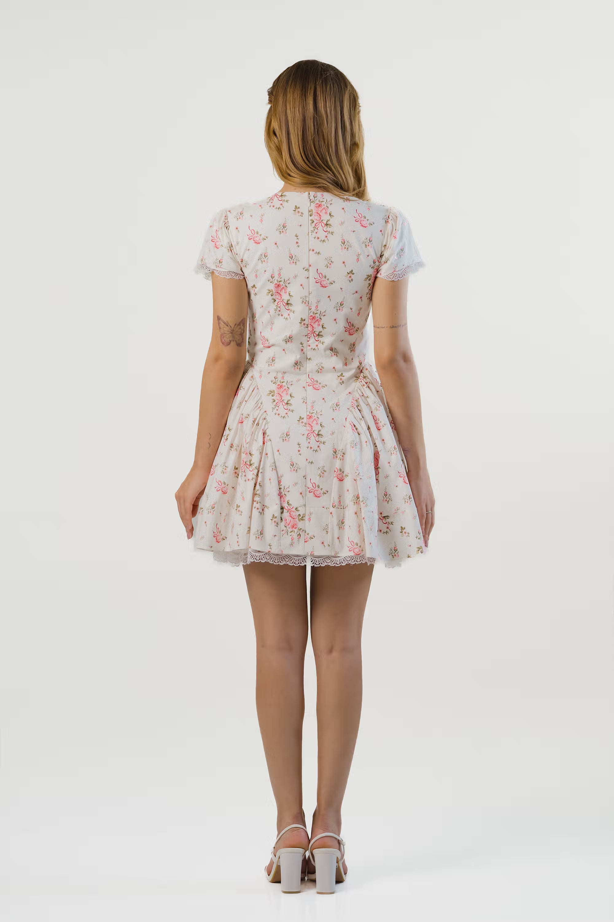 Back view of white floral mini dress showing pink floral print and lace hem