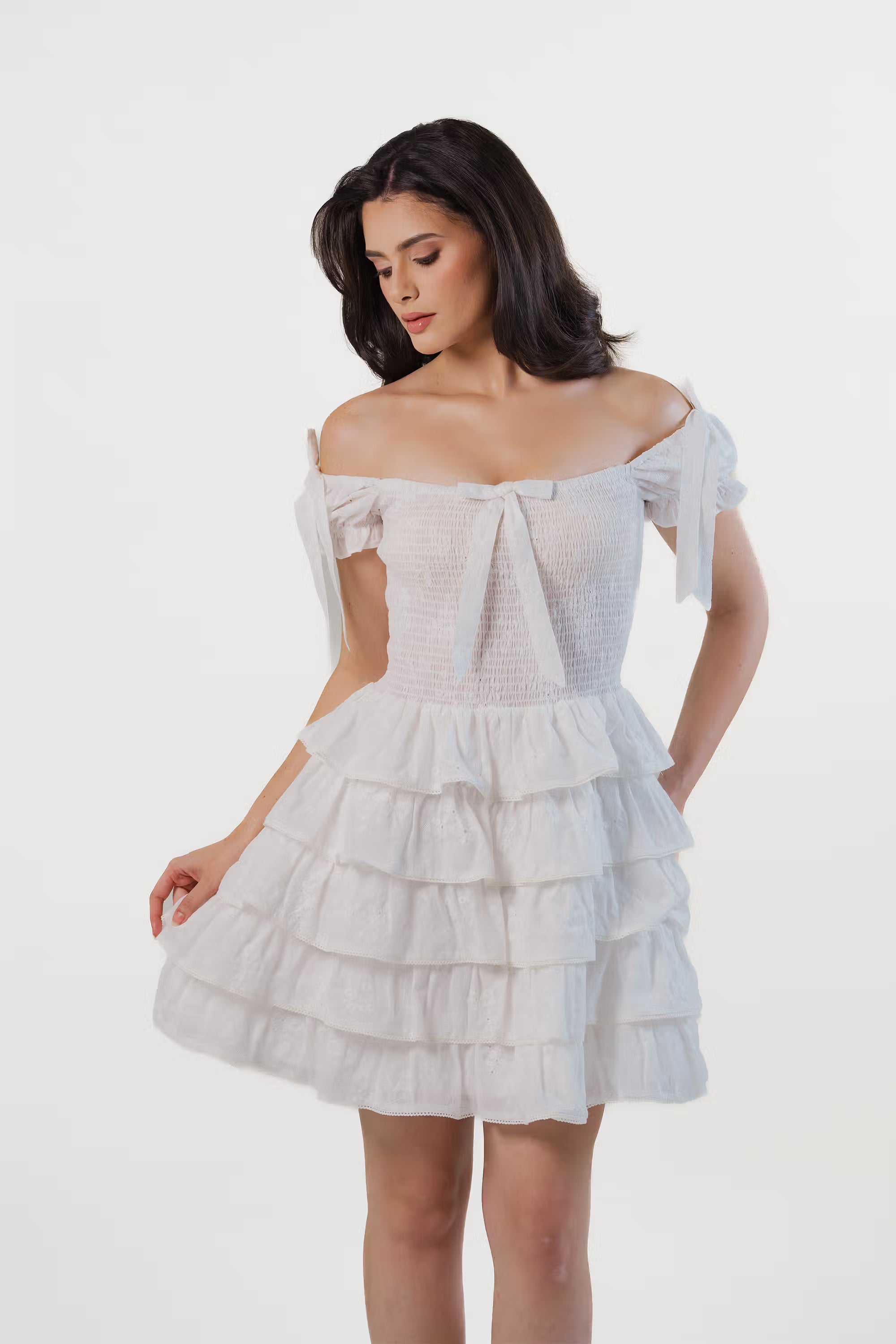 Woman wearing a white off-shoulder ruffle mini dress with tiered skirt, front view, summer party outfit.