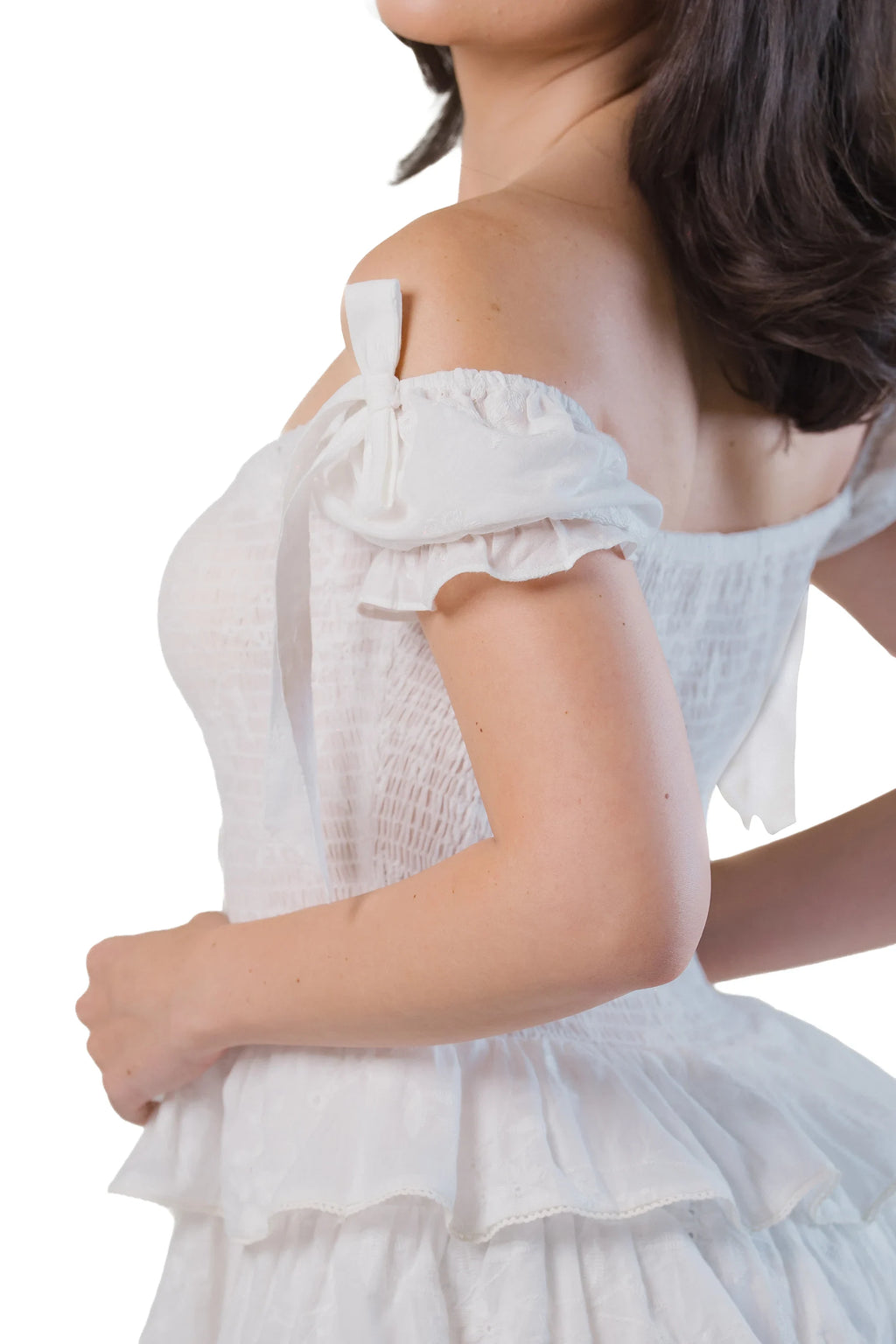 Off-shoulder sleeve tie close-up on white smocked mini dress