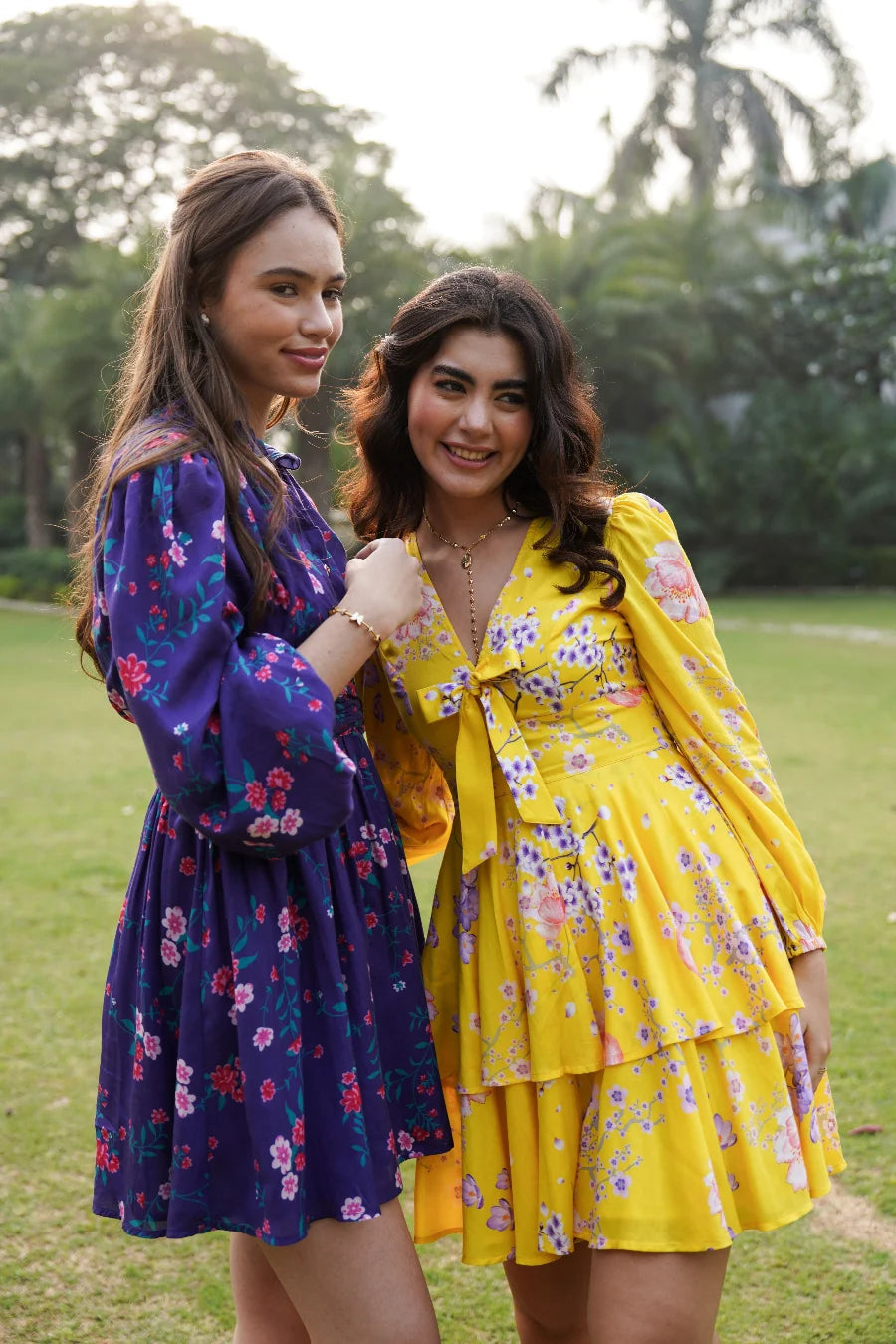 Women in floral tiered mini dresses posing outdoors in evening light