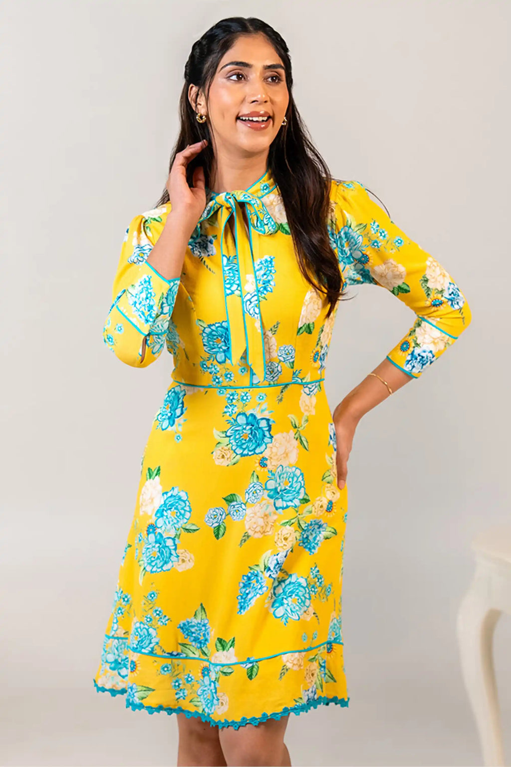 Woman in yellow floral bow tie short dress smiling