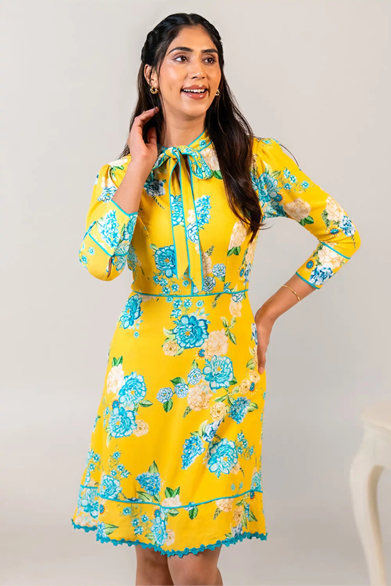 Woman in yellow floral bow tie short dress smiling