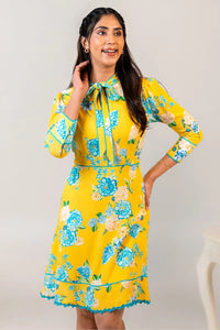 Woman in yellow floral bow tie short dress smiling