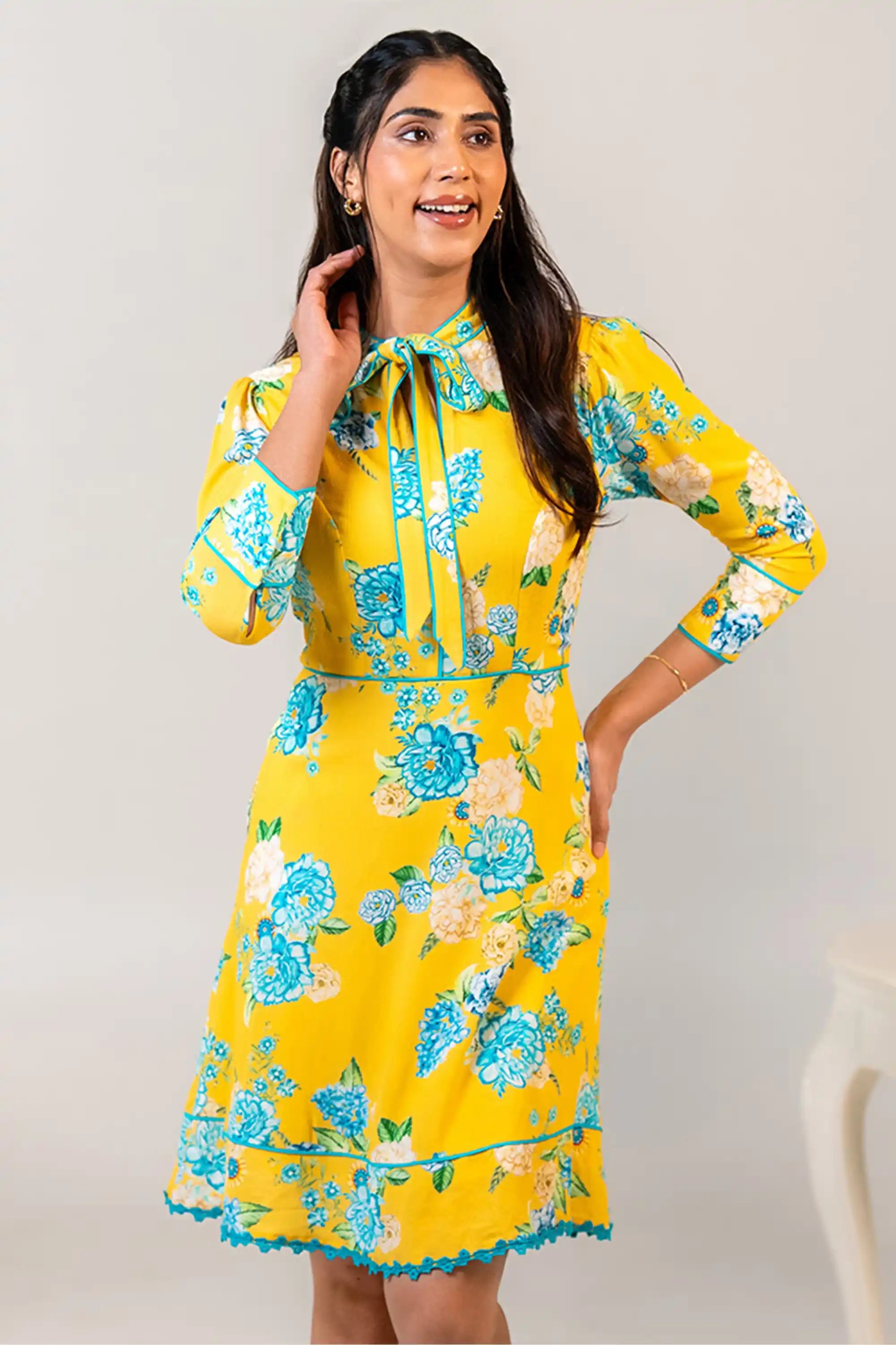 Woman in yellow floral bow tie short dress smiling
