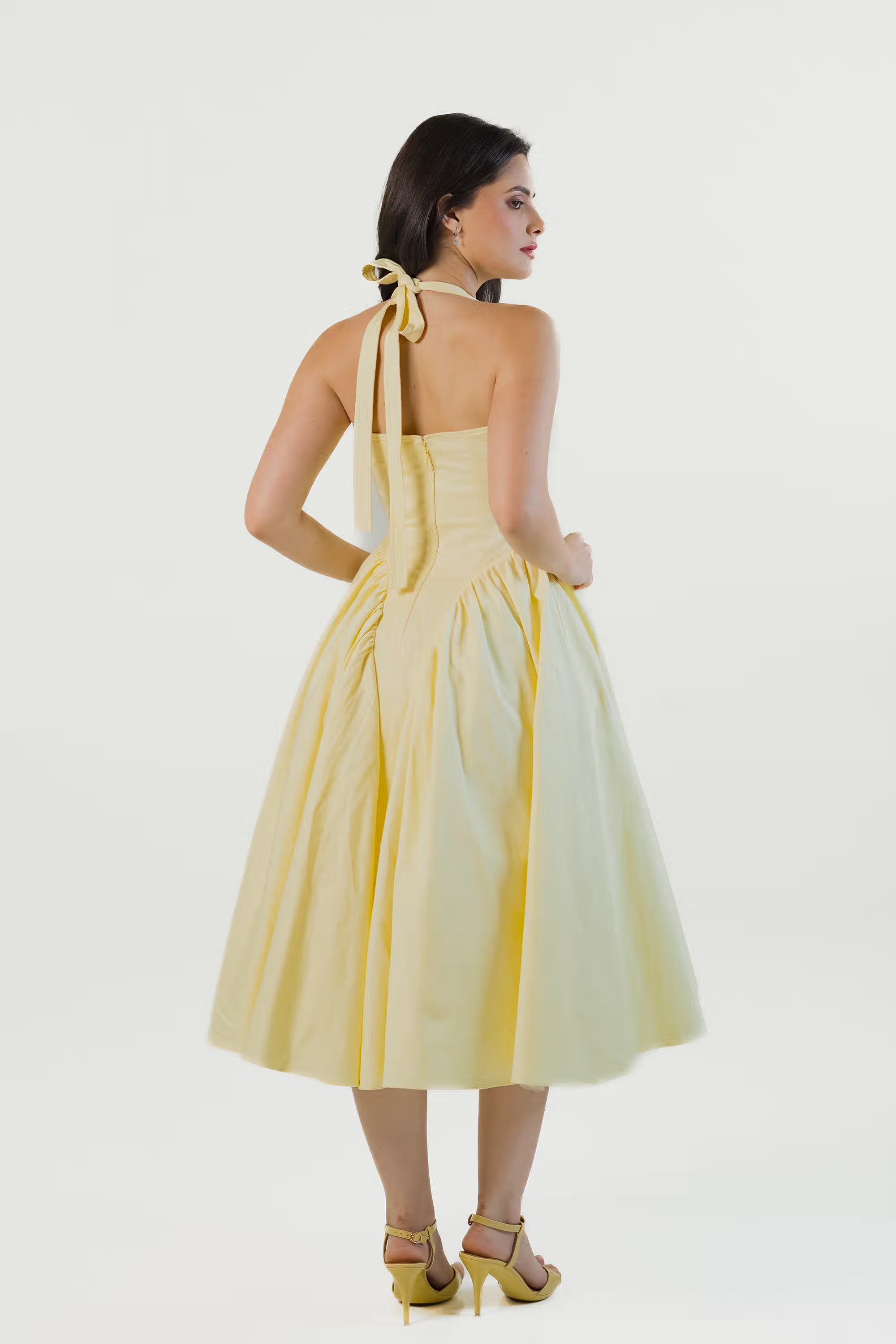 Yellow halter dress close-up showing V-neckline, fitted bodice, and waist detail