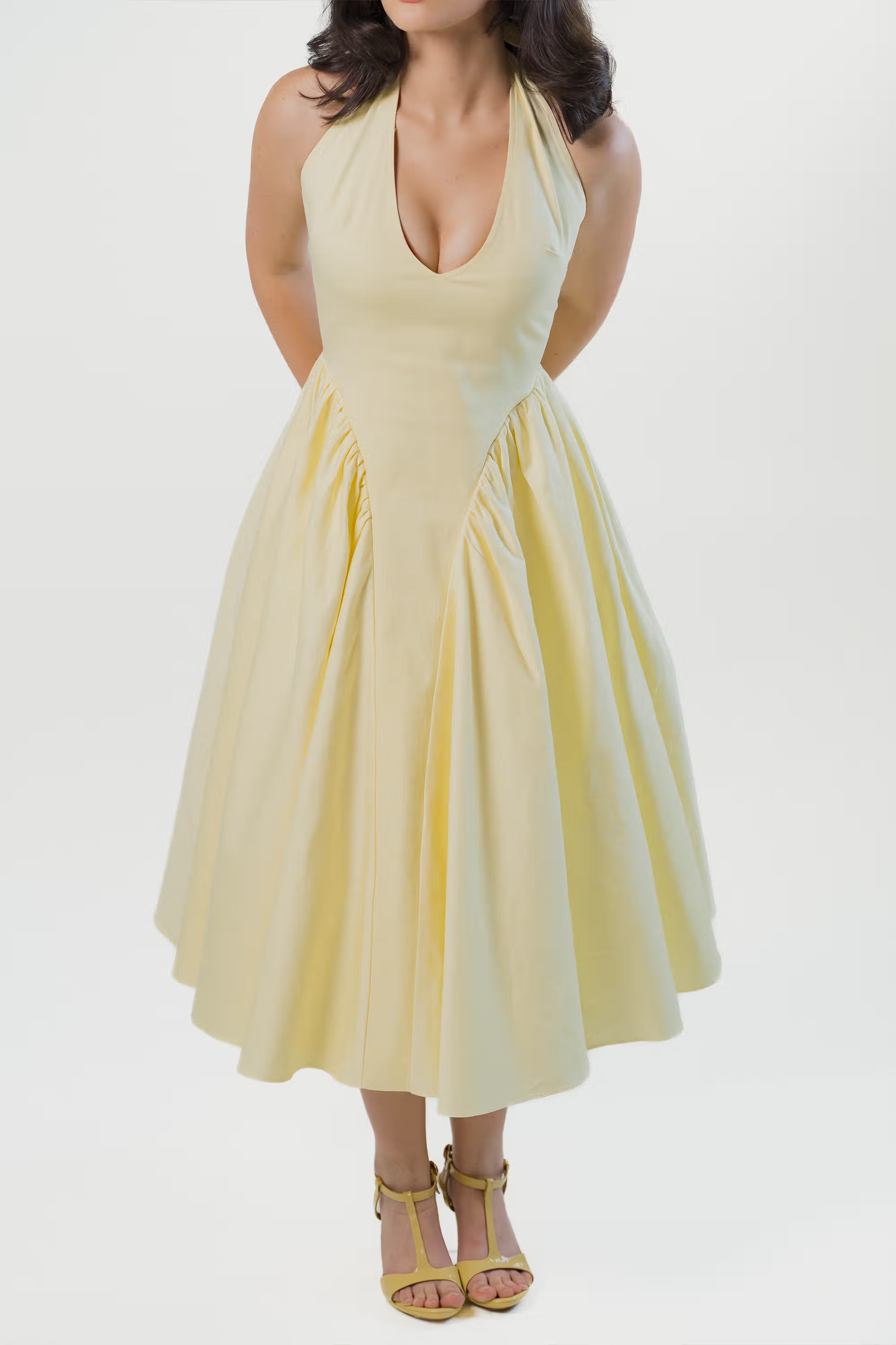 Model in yellow halter neck midi dress with plunging neckline and gathered waist panels